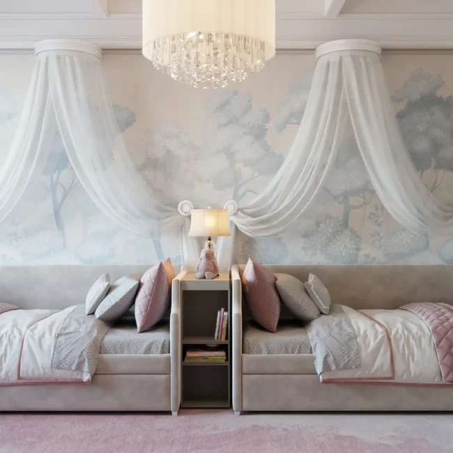 An elegant neoclassical bedroom for two girls featuring blush pink spindle chairs at a shared workspace and two daybeds set against a whimsical forest mural with delicate white canopies.