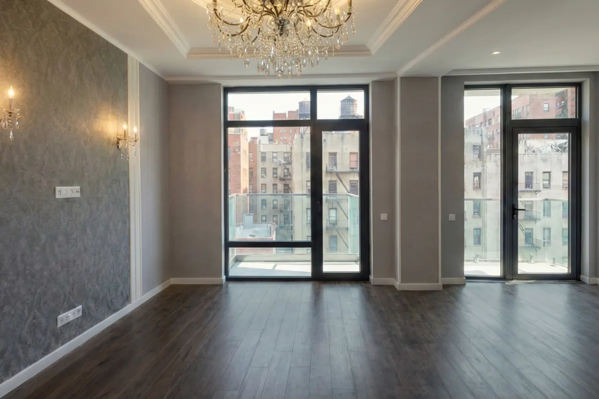 Renovated Manhattan living room featuring grey damask wallpaper, a crystal chandelier, dark wood floors, and balcony access with city views.