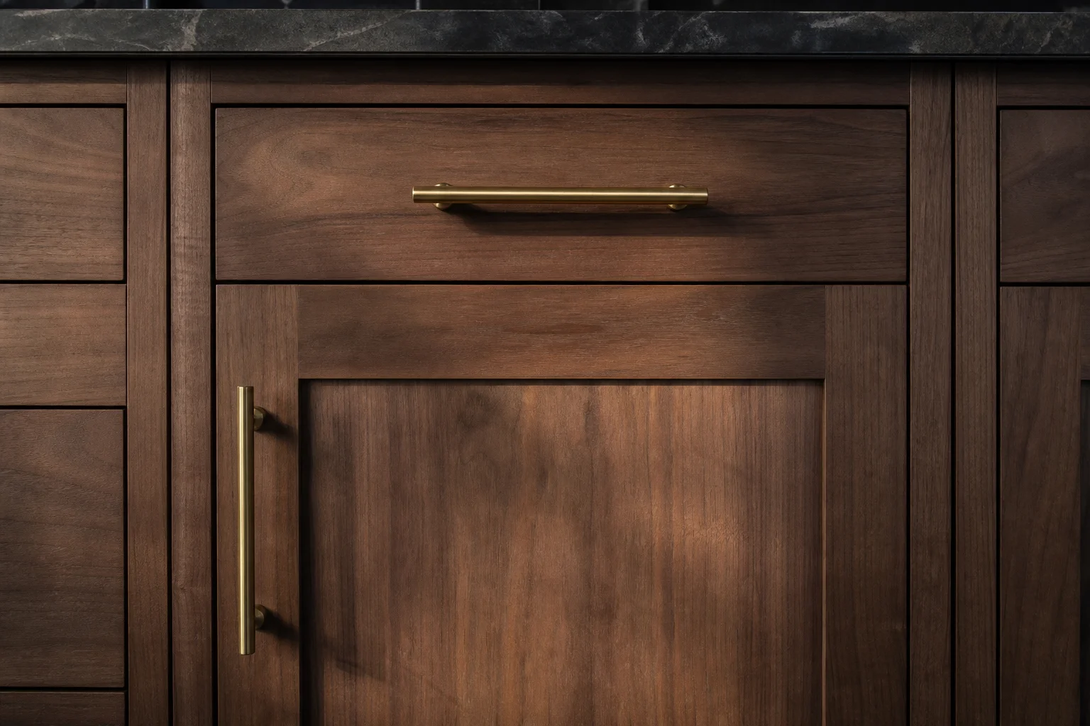 Close-up of walnut cabinet door with brushed brass bar pull