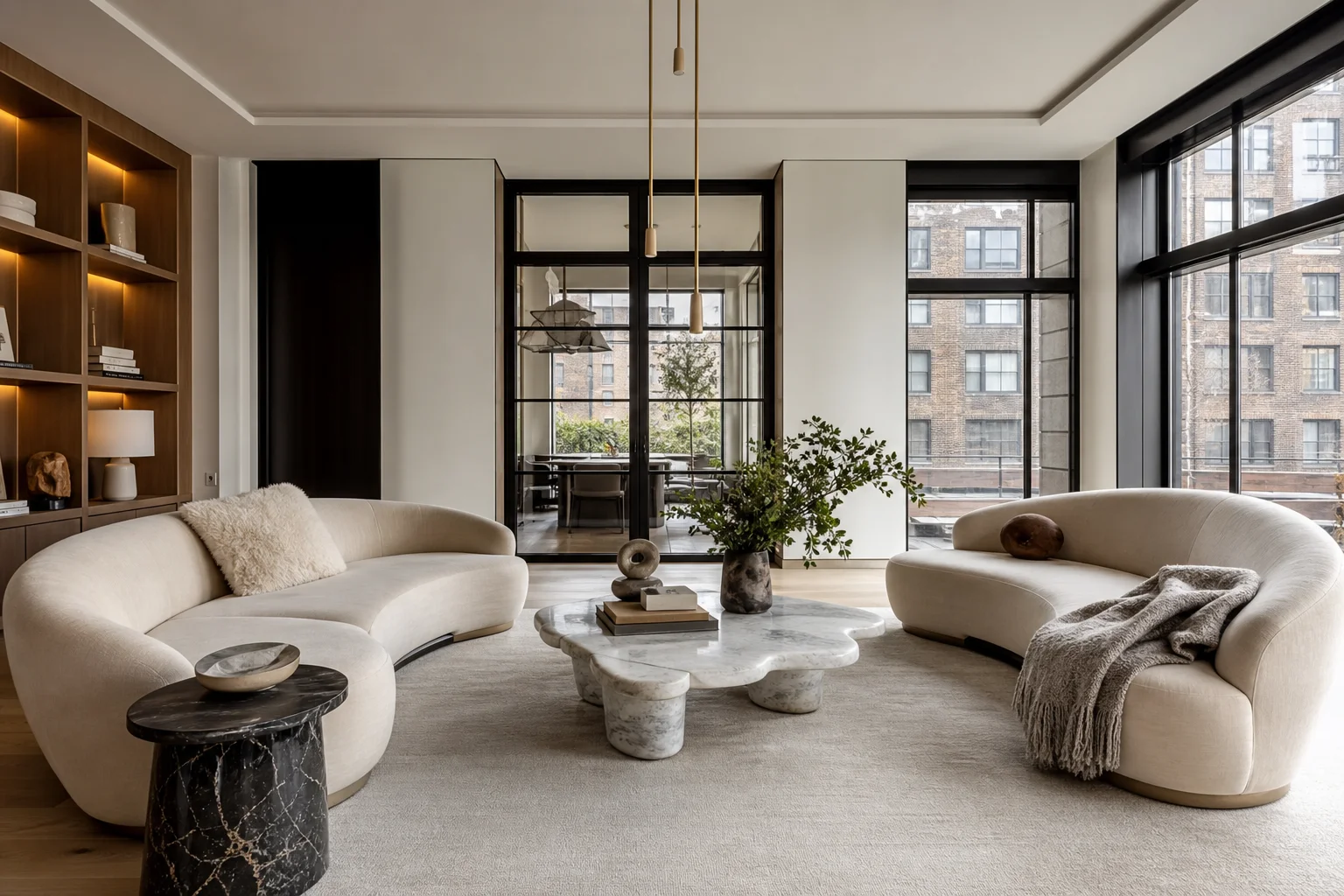 Living room with two cream sofas facing each other, marble coffee table, and large black-framed windows showing neighboring brick building