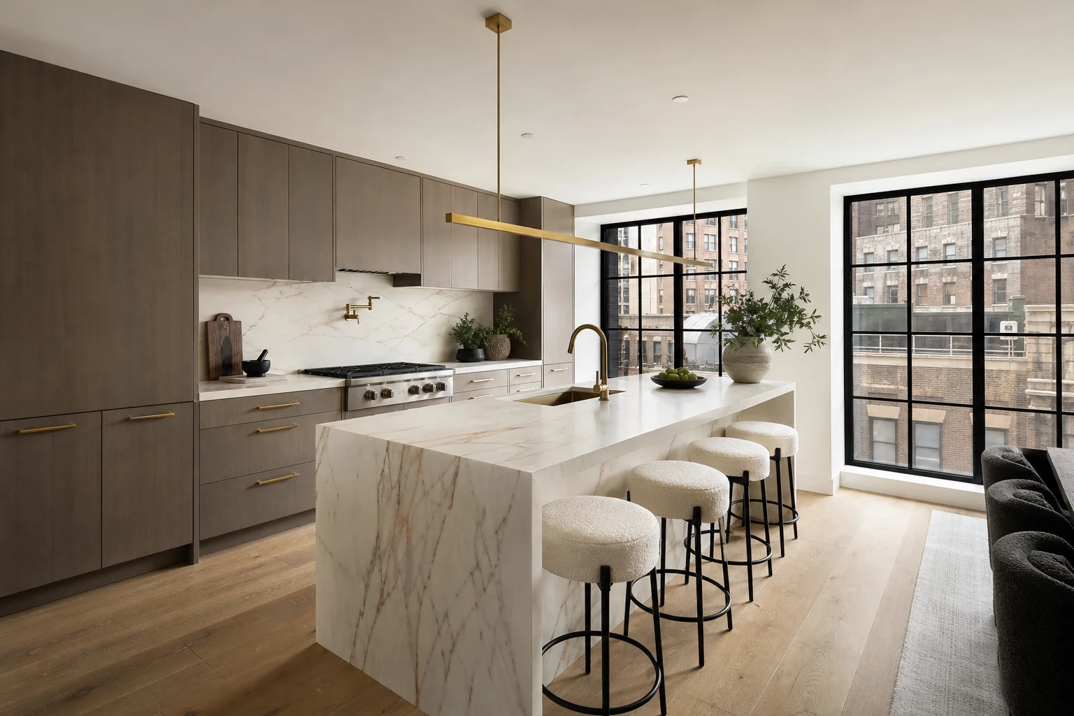 Luxury kitchen with honed Calacatta island, warm taupe cabinets and Wolf range, Manhattan window view