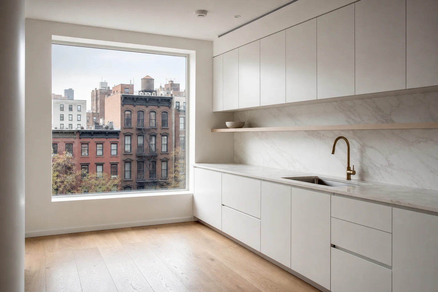 All-white kitchen with flat-front handleless cabinets and marble countertop in Manhattan apartment