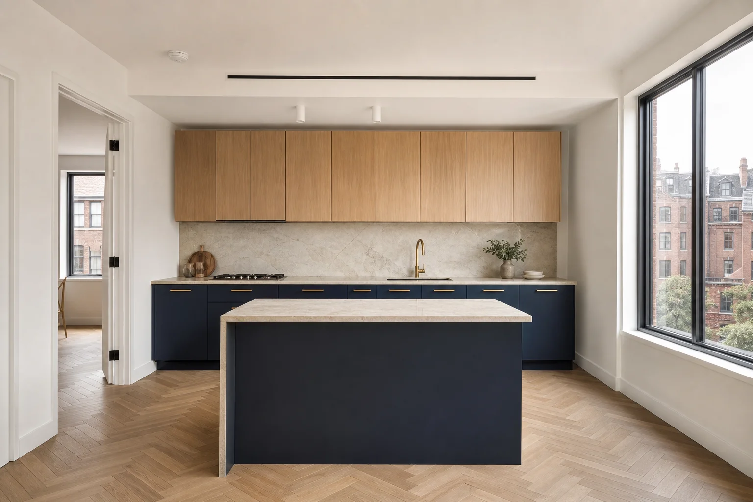 Navy blue lower cabinets with white oak uppers and brass hardware in Manhattan kitchen with herringbone parquet