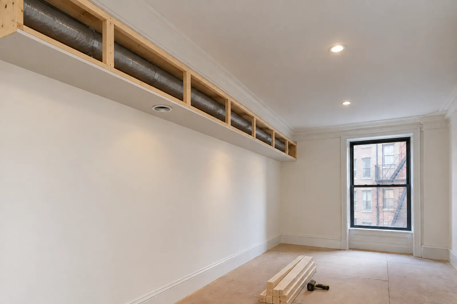 New soffit framed under a pre-war plaster ceiling with two small round air conditioning ducts running inside it